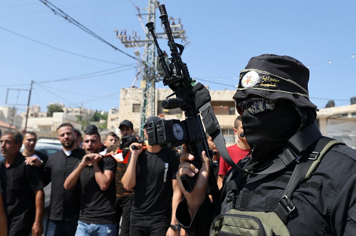 EDITORS NOTE: Graphic content / A fighter affiliated with the Palestinian Islamic Jihad movement, marches as men carry the body of Dhurar al-Kafrini, reportedly killed during clashes with Israeli forces in the Jenin refugee camp, during his funeral a the camp in the occupied West Bank, on August 2, 2022. A 17-year-old Palestinian was shot dead by Israeli forces during a late raid on August 1, 2022, in the flashpoint West Bank district of Jenin. Islamic Jihad identified the teenager as al-Kafrini, and said he was a member of the group and "our heroic martyr". (Photo by JAAFAR ASHTIYEH / AFP)