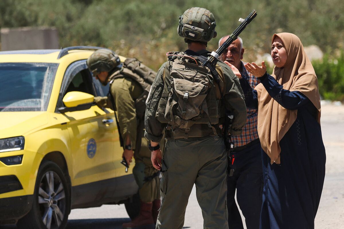 Israeli soldiers speak to people trying to enter the West Bank town of Yabad, after they closed its entrance to traffic, as they search for armed attackers involved in shooting incidents a day before, on June 14, 2023. An Israeli was wounded in a shooting near the town of Yabad on June 13, and four soldiers were injured in an exchange of fire as they were pursuing the assailants from that attack, who are still at large. (Photo by Jaafar ASHTIYEH / AFP)