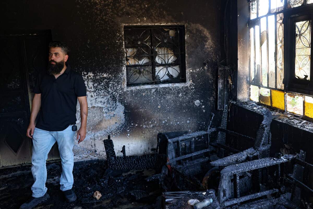 A man stands inside a home set on fire by Israelis in Turmus Aya near the occupied West Bank city of Ramallah, on June 21, 2023. A resident of Turmus Ayya told AFP around "200 settlers" attacked the Palestinian village, while AFP journalists in the village saw scorched homes, buildings and wounded people being evacuated by ambulance. (Photo by AHMAD GHARABLI / AFP)