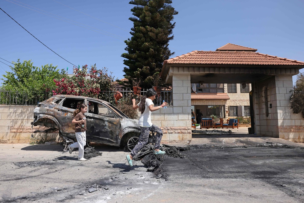 Palestinians walk past a burnt car, which was set on fire by Israeli settlers the day before, in Turmus Aya near the occupied West Bank city of Ramallah, on June 22, 2023. A resident of Turmus Ayya told AFP around "200 settlers" attacked the Palestinian village, while AFP journalists in the village saw scorched homes, buildings and wounded people being evacuated by ambulance. (Photo by AHMAD GHARABLI / AFP)