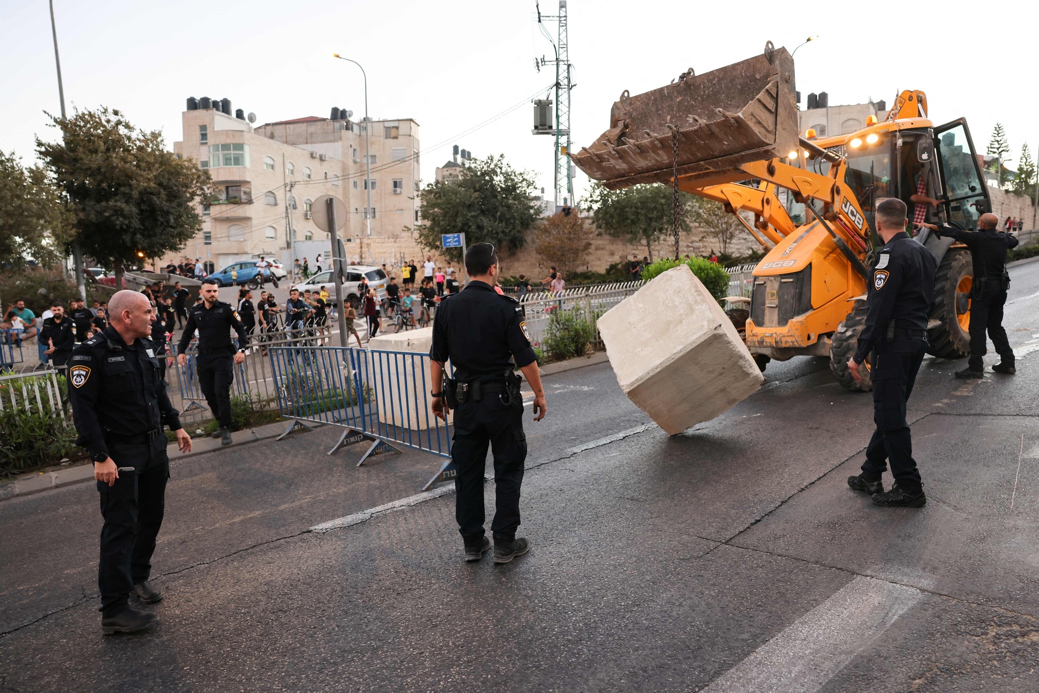 Israeli policemen place cement blocks across a road linking the east Jerusalem Arab neighbourhood of Beit Hanina with west Jerusalem before the start of Yom Kippur (Day of Atonement), the most important day in the Jewish calendar which starts at sunset, on September 24, 2023. (Photo by AHMAD GHARABLI / AFP)