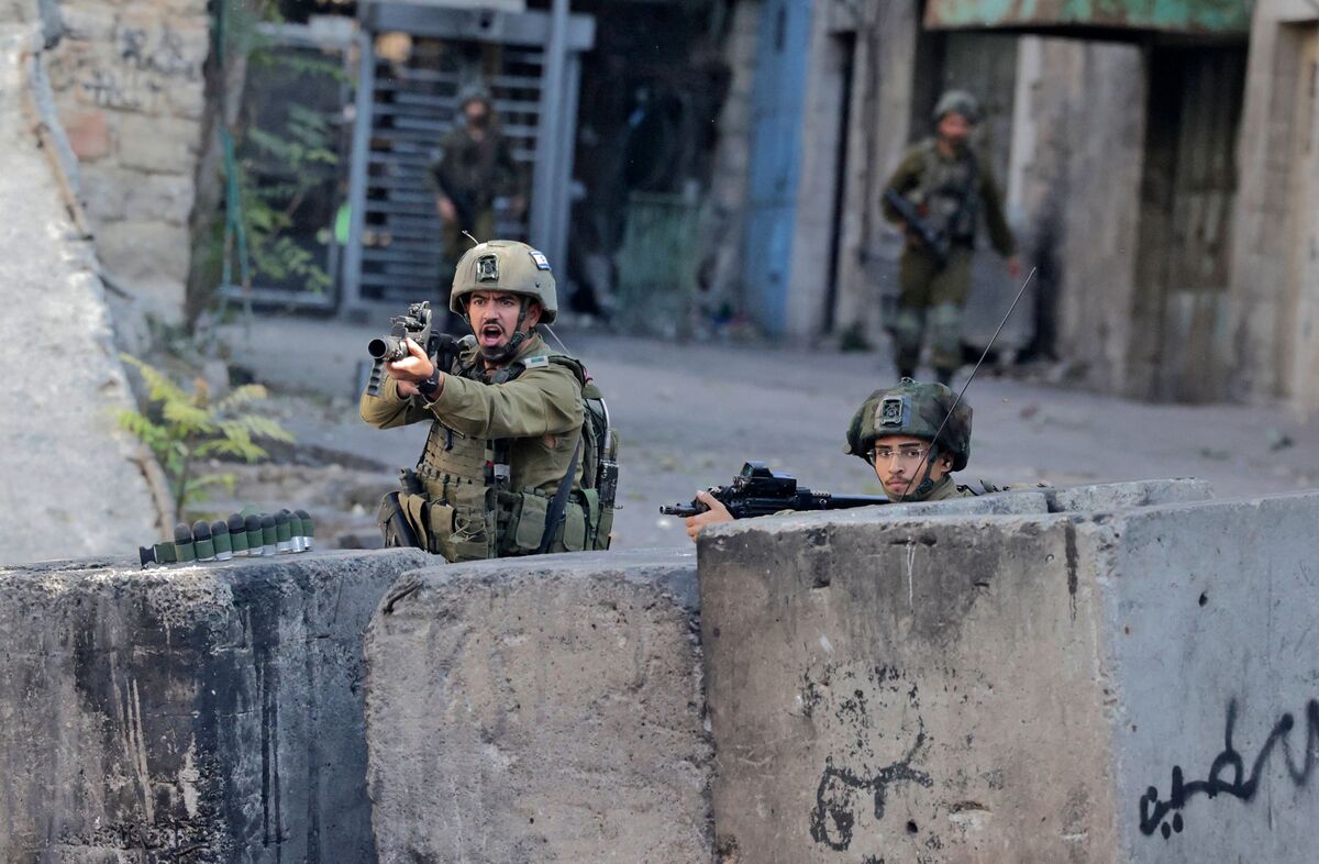 Israeli security forces take cover from Palestinian stone-throwers amid clashes in the West Bank city of Hebron on November 4, 2022. (Photo by HAZEM BADER / AFP)