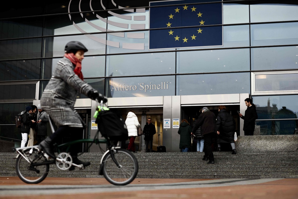 A woman rides near the entrance of the European Parliament in Brussels on December 9, 2022. Belgium on December 9, 2022 detained four people including a former MEP as part of a probe into suspected corruption by "a Gulf country" at the EU parliament, the prosecutor's office said. (Photo by Kenzo TRIBOUILLARD / AFP)