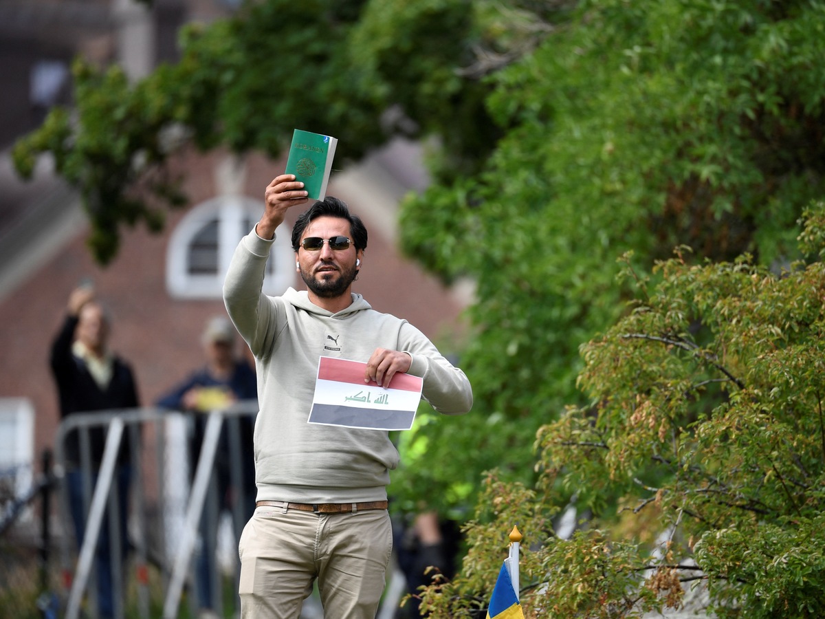 Protestor Salwan Momika holds up the Muslim holy book and a sheet of paper showing the flag of Iraq during a protest outside the Iraqi Embassy in Stockholm, Sweden, on July 20, 2023. Iraq warned Sweden on July 20, 2023 that it would cut diplomatic relations if a Koran-burning protest is allowed to go ahead in Stockholm, after protesters stormed and torched the Swedish embassy in Baghdad overnight. (Photo by Oscar Olsson / TT News Agency / AFP) / Sweden OUT (Photo by OSCAR OLSSON/TT News Agency/AFP via Getty Images)