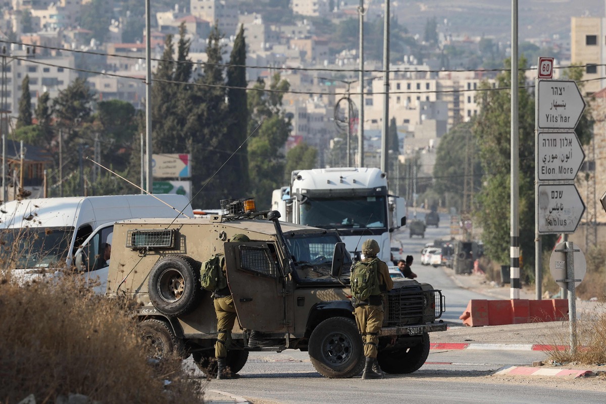 Israeli security forces stand guard after closing a road following a reported attack in the town of Huwara in the occupied West Bank, on August 19, 2023. Two Israelis were killed today in a suspected shooting attack in the occupied West Bank, the army said. (Photo by AHMAD GHARABLI / AFP)