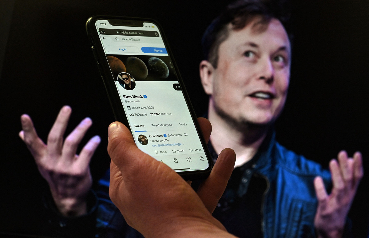 (FILES) In this file photo illustration, a phone screen displays the Twitter account of Elon Musk with a photo of him shown in the background, on April 14, 2022, in Washington, DC. Twitter shares slid late on July 7, 2022 after a Washington Post report that Elon Musk's $44 billion deal to buy the social media giant is in danger. - (Photo by Olivier DOULIERY / AFP)