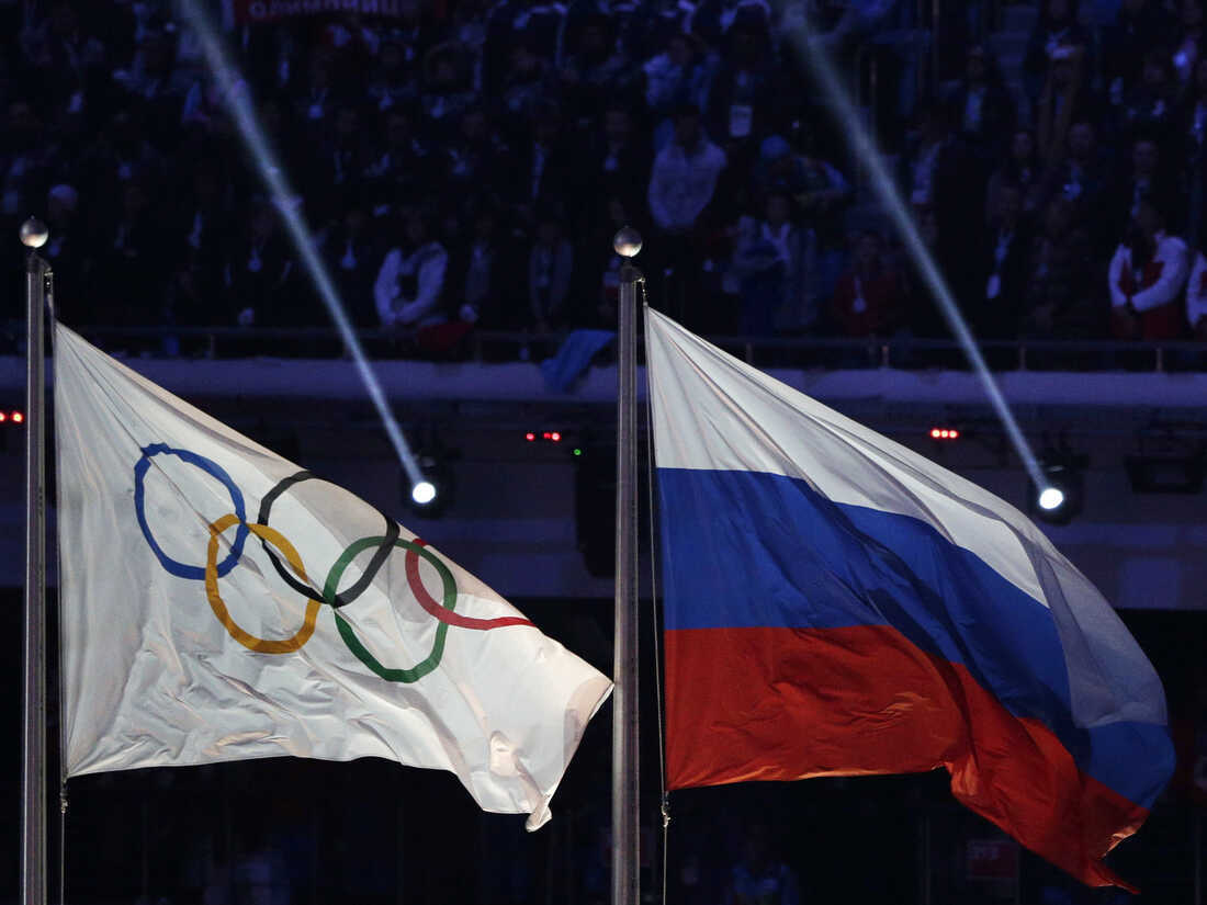 FILE - The Russian national flag, right, flies after it is hoisted next to the Olympic flag during the closing ceremony of the 2014 Winter Olympics in Sochi, Russia, Feb. 23, 2014. Track and field leaders signaled Thursday, March 23, 2023, that it will be nearly impossible for Russian and Belarusian athletes to compete at the Paris Olympics next year if the war in Ukraine continues. (AP Photo/Matthias Schrader, File)