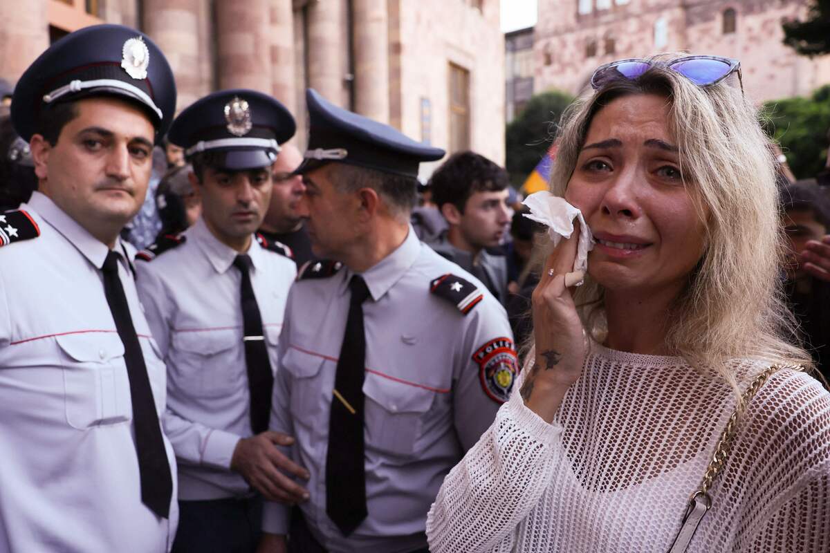 A woman (R) cries next to Armenian police officers in front of the Government House during a demonstration in Yerevan on September 21, 2023, following Azerbaijani military operations against Armenian separatist forces in Nagorno-Karabakh. Azerbaijan and Armenian separatists from the disputed territory of Nagorno-Karabakh held their first direct peace talks on September 21, 2023 after Baku claimed to have regained control over the breakaway region in a lightning military operation. (Photo by ALAIN JOCARD / AFP)