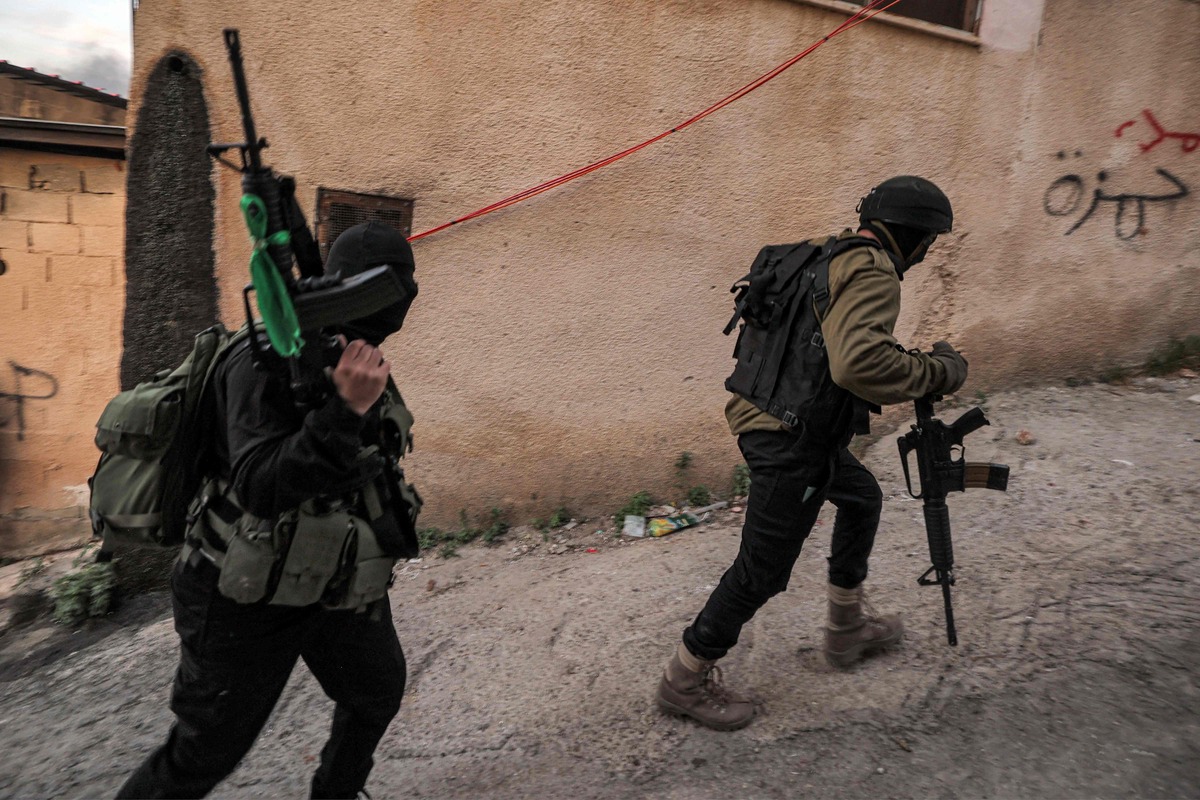 EDITORS NOTE: Graphic content / Masked Palestinian gunmen walk along an alley during an Israeli army raid in the Jenin camp for Palestinian refugees in the occupied West Bank on March 7, 2023. Israeli troops on March 7 killed six Palestinians and wounded 11 others during the raid in Jenin, the Palestinian health ministry said in an updated toll. Among the wounded, two had serious injuries, the ministry said in a statement. (Photo by JAAFAR ASHTIYEH / AFP)