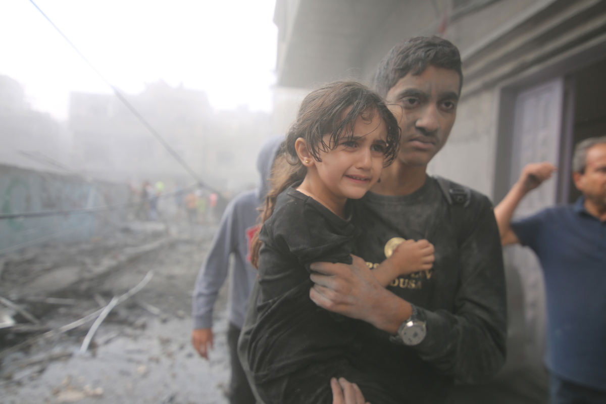 (231012) -- GAZA, Oct. 12, 2023 (Xinhua) -- A man holds a girl in his arms and evacuates from a building destroyed in Israeli airstrikes in the southern Gaza Strip city of Rafah, on Oct. 12, 2023. The death toll of the Palestinians from the ongoing Israeli strikes on Gaza hit 1,417, while another 6,268 were wounded, according to the Gaza-based health ministry. (Photo by Khaled Omar/Xinhua)