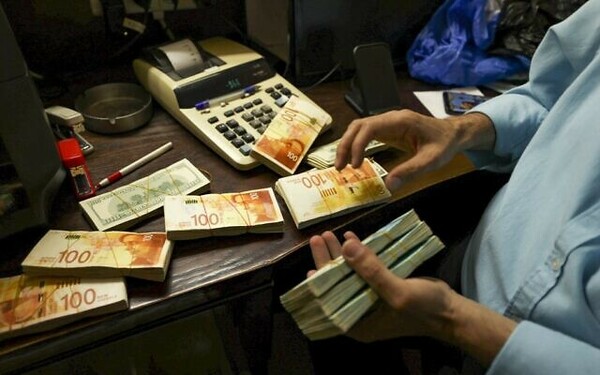 A Palestinian man counts stacks of banknotes at a currency exchange counter in the West Bank city of Ramallah on October 5, 2021. - Palestinian businesses flush with too much Israeli cash, much of it brought in by the tens of thousands of Palestinians who work inside Israel or Jewish settlements in the West Bank, but experts say the buildup of hard currency risks stifling the Palestian financial system. (Photo by ABBAS MOMANI / AFP)