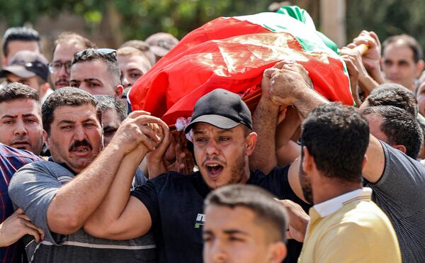 Mourners carry the Palestinian flag-draped body of Salah Sawafta, who was killed earlier during a raid by Israeli forces, in the city of Tubas in the north of the occupied West Bank on August 19, 2022. The 58-year-old Sawafta "died of critical wounds, sustained by live bullets from the occupation (Israeli military) in the head, in Tubas this morning", the Palestinian health ministry said in a statement. The Israeli military said soldiers had come under fire during a raid in the town aimed at apprehending "a group of terrorists" planning attacks on Israeli civilians. (Photo by JAAFAR ASHTIYEH / AFP)