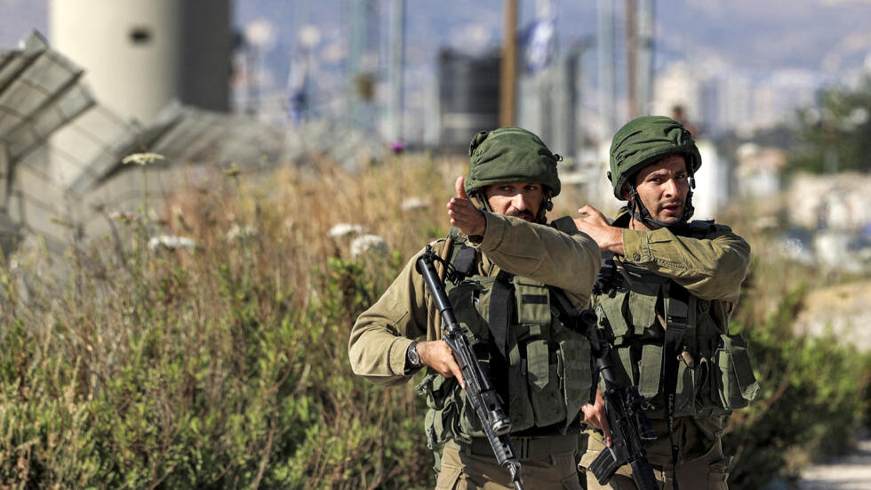 Israeli army soldiers confront journalists approaching the Israeli-controlled Hawara checkpoint after an attempted stabbing attack there, near Nablus in the occupied West Bank on May 17, 2022. (Photo by JAAFAR ASHTIYEH / AFP)