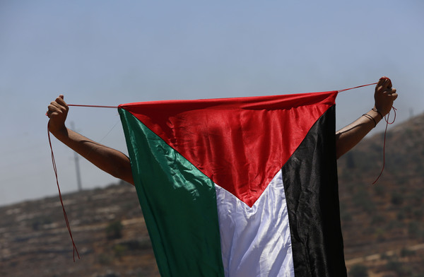 (210625) -- NABLUS, June 25, 2021 (Xinhua) -- A protester holds a Palestinian flag during clashes with Israeli soldiers and members of Israeli border police following a protest against the expansion of Jewish settlements in the village of Beita, south of the West Bank city of Nablus, June 25, 2021. (Photo by Ayman Nobani/Xinhua)