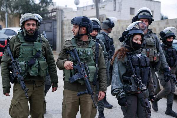 Israeli soldiers stand guard on the street where the apartment of Mohammad al-Jaabari, a Palestinian who carried out a shooting attack last year, was demolished by a controlled explosion in Hebron in the occupied West Bank early on February 16, 2023. Jaabari had opened fire on Israeli settlers near the settlement of Kiryat Arba in the southern West Bank, killing one and wounding four in October 2022. (Photo by HAZEM BADER / AFP)