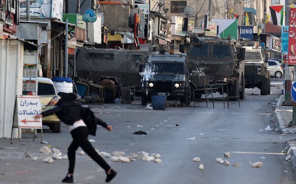 Palestinian protesters hurl rocks at members of the Israeli army during a reported raid in the Palestinian Askar refugee camp near Nablus in the occupied West Bank, on December 18, 2022. (Photo by JAAFAR ASHTIYEH / AFP)