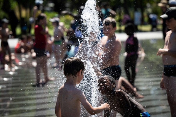 Children cool off with the water of a fountain, as the air temperature exceeds 30 degrees Celsius in Nantes, western France, on July 13, 2022. (Photo by Loic VENANCE / AFP)