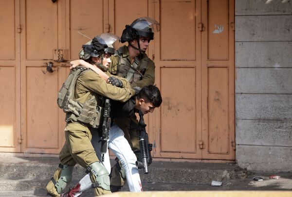 Israeli soldiers detain a Palestinian youth during clashes in the city of Hebron in the occupied West Bank on October 25, 2022. (Photo by HAZEM BADER / AFP)