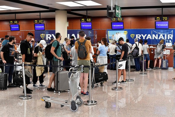 Passengers queue at the Ryanair check-in counters at the Terminal 2 of El Prat airport in Barcelona on July 1, 2022. At least nine flights, eight with Easyjet and one with Ryannair, departing and arriving from Spain were canceled today due to a strike, and at least 134 flights were delayed, in the middle of the high tourist season. The social movement, aimed at demanding better working conditions for the 1,900 cabin crew in Spain, began at the end of last week and could last until July 2. (Photo by Pau BARRENA / AFP)