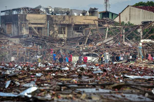 TOPSHOT - People look at the aftermath of destroyed homes after an explosion ripped through a firework warehouse, killing nine people and injuring more than 100, in Sungai Kolok district in the southern Thai province of Narathiwat on July 29, 2023. (Photo by Madaree TOHLALA / AFP)