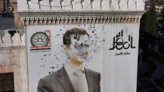 This aerial picture shows a bullet-riddled portrait of Syrian President Bashar al-Assad adorning Hama's municipality building after it was defaced following the capture of the city by anti government fighters, on December 6, 2024. Rebel forces pressing a lightning offensive in Syria aim to overthrow President Bashar al-Assad's rule, their Islamist leader said in an interview published on December 6. In little over a week, the offensive has seen Syria's second city Aleppo and strategically located Hama fall from Assad's control for the first time since the civil war began in 2011. (Photo by Omar HAJ KADOUR / AFP)